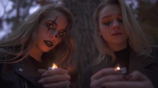 Two caucasian blonde women with halloween makeup holding small candles in hands and looking at the camera. Gothic horror night. — Stock Video