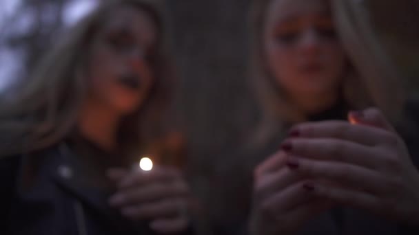 Δύο ξανθιά κορίτσια με τρομακτική μακιγιάζ αποκριών κρατώντας μικρά κεριά στα χέρια και κοιτάζοντας την κάμερα. Γοτθική βραδιά τρόμου. Λευκές γυναίκες έτοιμες για τη νύχτα όλων των Αγίων. — Αρχείο Βίντεο