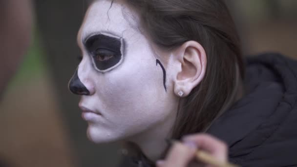 Dia das Bruxas. Maquiagem artista aplica maquiagem para o rosto feminino — Vídeo de Stock