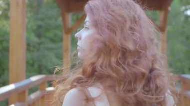 Kırmızı saçlı güzel ince kadın köprüde yürüyor sonra dönüp kameraya bakıyor. Dışarıda boş zaman. Parkta yürüyen kız. Doğayla bağlantı. Close