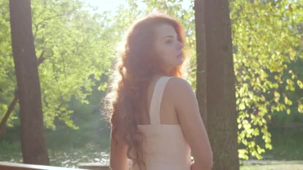 Bastante pelirroja pensativa mujer dando la vuelta y mirando hacia otro lado. Joven chica caucásica tomando el sol en el parque de otoño . — Vídeos de Stock