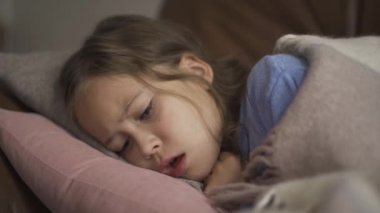 Hasta genç beyaz kız evde battaniyenin altında yatarken öksürüyor. Çocuğun ateşi var. Sağlık kavramı, hastalık, hastalık, soğuk algınlığı, tedavi