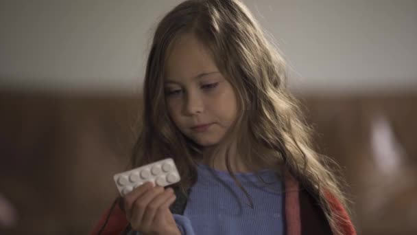 Κοντινό-up πρόσωπο της άρρωστης καυκάσιας κορίτσι επιλογή μεταξύ χάπια και λεμόνι και κοιτάζοντας την κάμερα ενώ κάθονται στο σπίτι. Παραδοσιακή και εναλλακτική ιατρική. Έννοια της υγείας, ασθένεια, αρρώστια, κρύο — Αρχείο Βίντεο