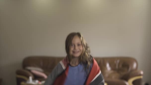 Heureuse fille caucasienne couverte de châle chaud tournant autour dans la chambre. La fille guérie après la maladie. Concept de santé, maladie, rhume, traitement — Video