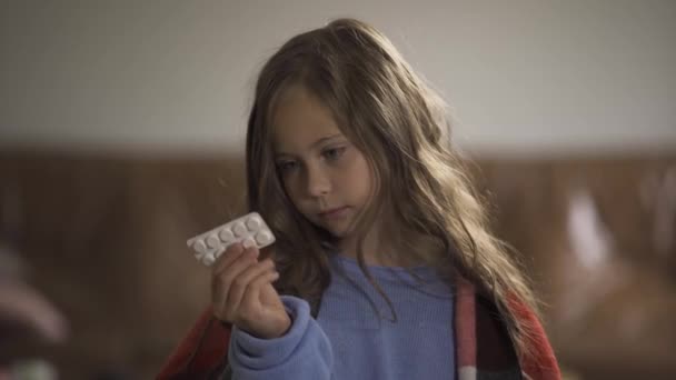 Menina branca bonito escolher entre pílulas e limão para o tratamento. Medicina tradicional e alternativa. Pequena criança alegre sentada em casa com um resfriado . — Vídeo de Stock