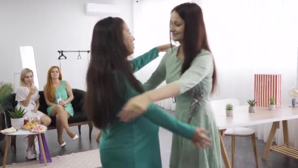 Twee blanke vrouwen knuffelen strak en glimlachend. Brunette meisje omarmt haar zwangere vriend. Vrouwelijk bedrijf viert pre-Birth Party. — Stockvideo