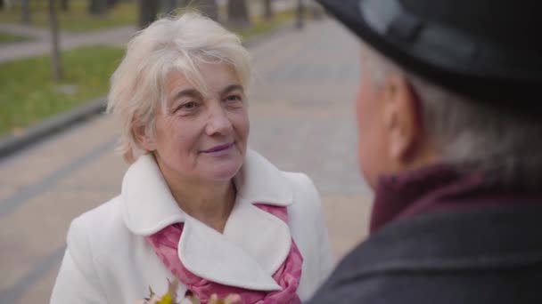 Senior blanke man zet krans gemaakt van gele bladeren op het hoofd van zijn schattige vrouw. gelukkig volwassen paar besteden herfst dag buiten. — Stockvideo