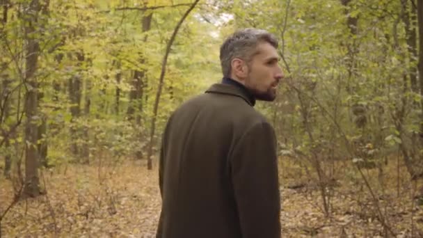 Vista posterior de un hombre caucásico adulto de pie en el bosque y mirando a su alrededor. Chico en ropa casual disfrutando tranquilo tranquilo otoño día solo . — Vídeos de Stock