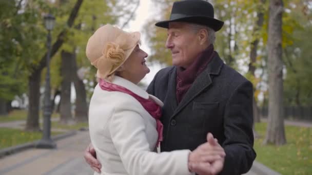 Smiling mature Caucasian couple dancing on the alley in the autumn park. Positive senior family dating outdoors. — Stock Video