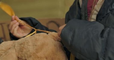 Kirli giysiler içinde oyuncak ayının üzerine donmuş parmaklarıyla fiyonk bağlamaya çalışan küçük kadın elleri. Sokakta yaşayan yalnız evsiz kız..