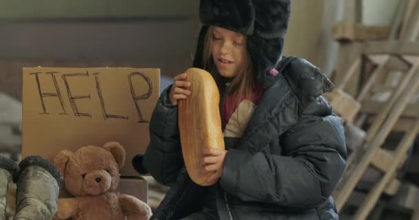 Retrato de um refugiado sírio a cheirar o pão e a parti-lo para comer. Menina sem-teto com fome fazendo um lanche . — Vídeo de Stock