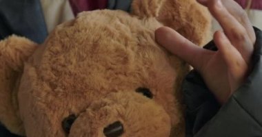 Kirli evsiz kızların oyuncak ayıyı tuttukları son derece yakın çekim. Mülteci yorgun, sevimli oyuncağını okşuyor..