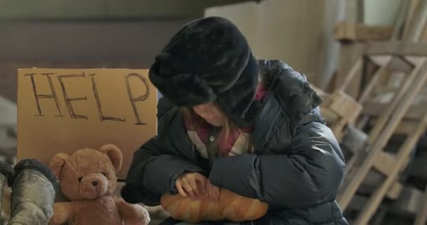 Portré egy hajléktalan kaukázusi lányról, akinek koszos az arca, és mohón eszi a kenyeret. Éhes gyermek él az utcán. — Stock videók