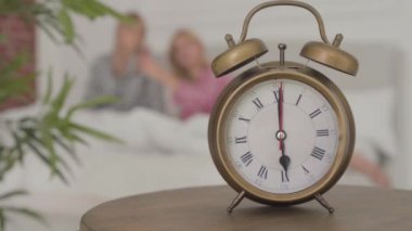 Akşam 6 'da, arkasında iki sarışın beyaz kadının yattığını gösteren eski moda bir çalar saatin yakın çekimi. Evdeki pijama partisinden sonra kızlar dinleniyor..