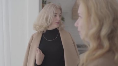 Arkadaşlarıyla konuşan ve gülümseyen beyaz bir kadının portresi. Olumlu olgun kadınlar hayatlarını tartışıyorlar. Arkaplana odaklanmış.