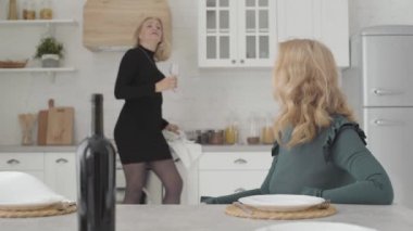 Gülümseyen Kafkas kadınları lüks mutfakta bir şişe şarapla oturup sohbet ediyorlar. Zarif elbiseli güzel olgun bayanlar evde dinleniyor..
