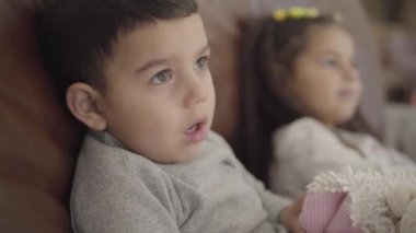 Orta Doğulu bir çocuğun, kız kardeşiyle arabada oturduğu yakın plan yüzü. Çocuk akşamını ailesiyle rahat bir evde geçiriyor..