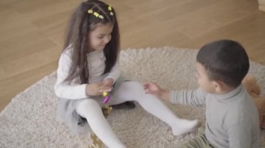 Oyuncak için savaşan iki tatlı Orta Doğulu çocuk. Erkek kardeşi parti düdüğünü kız kardeşinden almaya çalışıyor. Kardeşler evdeki yumuşak halıda oturuyor..