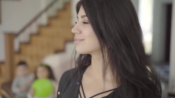 Close-up face of a happy Middle Eastern woman looking at her children sitting at the background and turning back to the camera. Smiling mother spending time with her son and daughter. — Stock Video