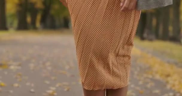 Close-up de um vestido de mostarda com tweed estampado pelo vento. Pernas femininas caucasianas que aparecem debaixo do vestido. Cinema 4k footage ProRes HQ . — Vídeo de Stock