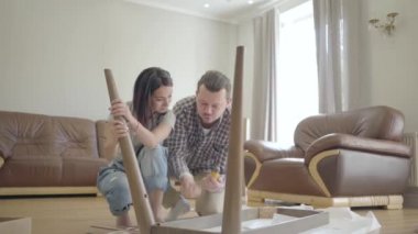 Oturma odasında toplanan beyaz bir ailenin portresi. Pozitif aile yeni evlerini dekore ediyor. İçeri giriyoruz..