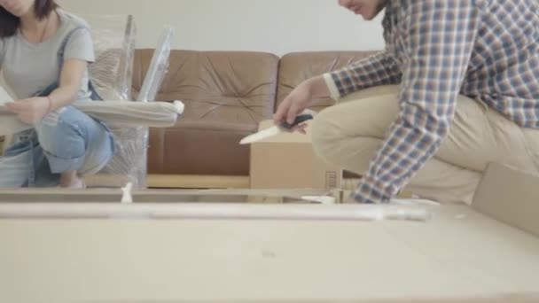 Young Caucasian family unpacking parcel in the living room. Happy couple furnishing their new house. Start of future life. Moving in. — Stock Video