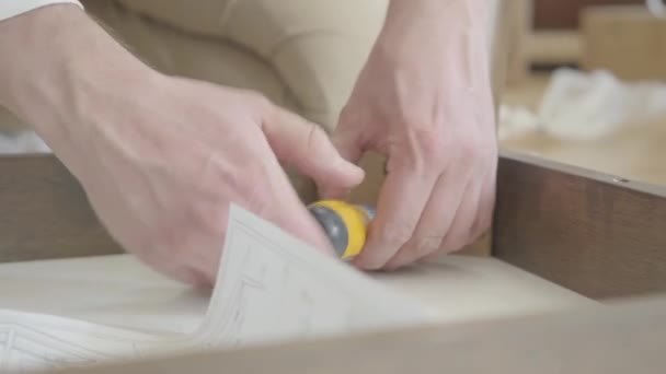 Primer plano de manos caucásicas apretando tornillos con destornillador. Cerrajero adulto que trabaja con muebles de madera . — Vídeos de Stock