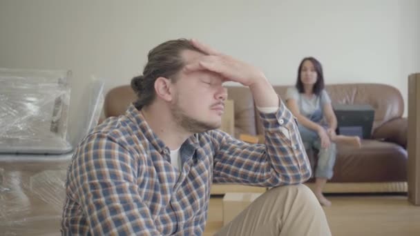 悲しい白人男性彼の妻やガールフレンドの背景に叫んで寺院をこすります.若い家の関係問題. — ストック動画