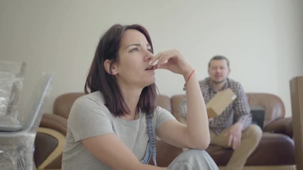 Naštvaná běloška sedící a dívající se stranou, zatímco její manžel nebo přítel křičí na pozadí. Problémy ve vztahu v mladé rodině. — Stock video