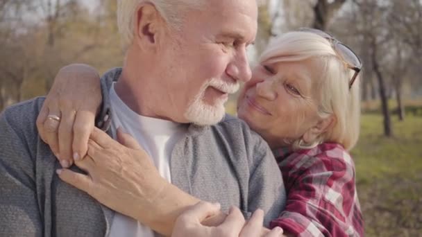 Zbliżenie portret białej szczęśliwej dojrzałej rodziny stojącej w słońcu w jesiennym lesie i przytulającej się. Starsza europejska para spędzająca słoneczny wieczór na świeżym powietrzu. Starzenie się razem, wieczna koncepcja miłości — Wideo stockowe