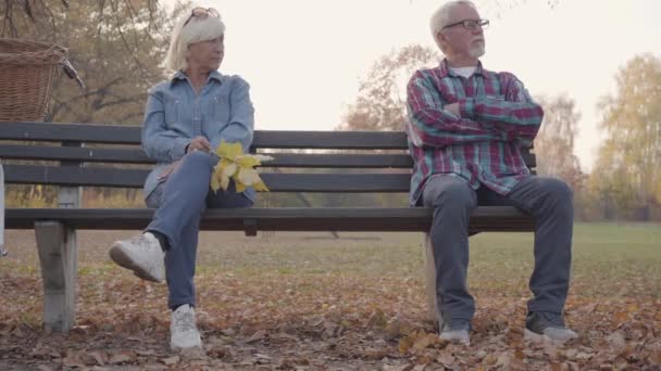 Αναστατωμένο ηλικιωμένο ζευγάρι Ευρωπαίων που κάθεται στον πάγκο ξεχωριστά. Η ώριμη οικογένεια καυκάσιων μάλωσε το απόγευμα του φθινοπώρου. Προβληματική σχέση, γήρανση μαζί. — Αρχείο Βίντεο