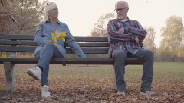 一对年长的欧洲夫妇单独坐在长椅上. 成熟的白人男子牵着他可爱的妻子，与家人和平相处。 一起变老，爱的概念. — 图库视频影像