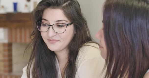 Retrato de close-up da jovem mulher branca inteligente em óculos elegantes olhando para sua amiga e sorrindo. Meninas bonitas passar o tempo livre em casa. Cinema 4k footage ProRes HQ . — Vídeo de Stock