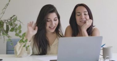 İki tatlı beyaz kız dizüstü bilgisayarlarıyla sızlanıyor ve görüntülü görüşme yapıyorlar. Kendine güvenen genç bayan arkadaşlar ya da kız kardeşler evde online sohbet ediyorlar. Sinema 4k görüntüleri Prores Hq.