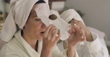 İki yetişkin Kafkasyalı kadın yüz maskelerini çıkarıyor. Havlu ve bornozlu güzel kızlar evde dinleniyor. Sinema 4k görüntüleri Prores Hq.