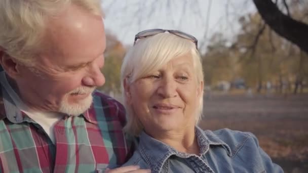 Primer plano de pareja caucásica madura positiva tomando selfie en el parque de otoño. Feliz familia europea moderna disfrutando de la jubilación juntos al aire libre. Envejecer juntos, concepto de amor eterno . — Vídeos de Stock