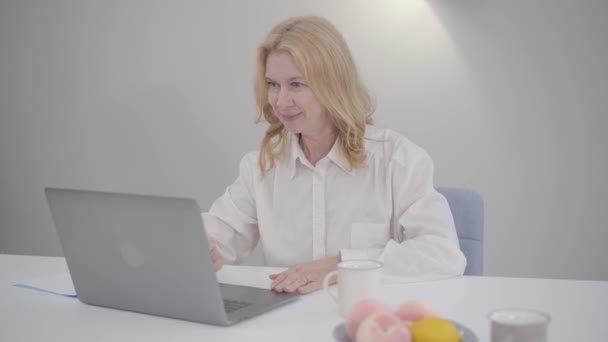 Olgun beyaz kadınlar dizüstü bilgisayarlarıyla oturup görüntülü görüşme yapıyorlar. Beyaz gömlekli kendine güvenen iş kadını evde internette sohbet ediyor. Serbest çalışma, modern online teknolojiler. — Stok video