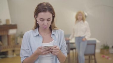 Portrait of young girl crying on the foreground. Mature blond Caucasian woman calming down her daughter at home. Sad adult lady sharing her problems with mother. Good family relationship, sympathy.