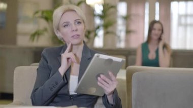 Kafede tablet kullanan düşünceli çekici bir kadın. Sosyal medyayı kullanan güzel sarışın beyaz iş kadınının portresi ya da restoranda internette sörf yapan. Cihaz bağımlılığı, yaşam tarzı, eğlence.