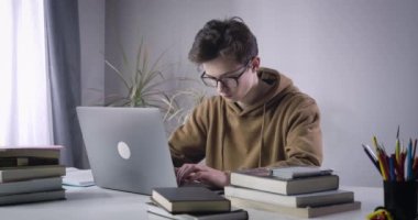 Laptop klavyesinde yazan gözlüklü esmer beyaz çocuk. İnternette okuyan ciddi bir üniversite öğrencisinin portresi. Zeka, e-öğrenme, yaşam tarzı. Sinema 4k ProRes Merkezi.