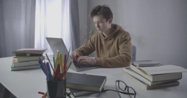 Çalışırken laptopun başında uyuyan yorgun Kafkasyalı öğrenci. Aşırı çalışan esmer çocuğun e-öğrenim portresi. Eğitim, aşırı çalışma, yaşam tarzı. Sinema 4k ProRes Merkezi.