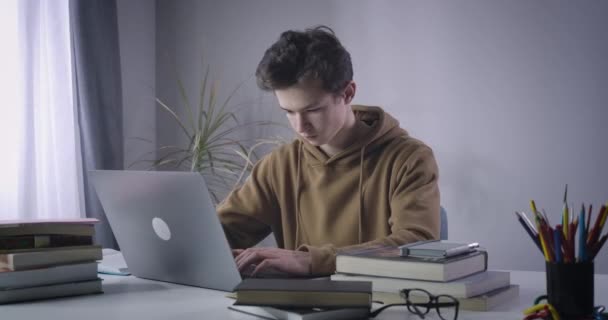不幸な白人の少年はノートパソコンからもたれ戻り、手をつないでいる。オンラインで勉強ストレス過労大学生の肖像画。ライフスタイル、疲労、教育。シネマ4k｜ProRes HQ. — ストック動画