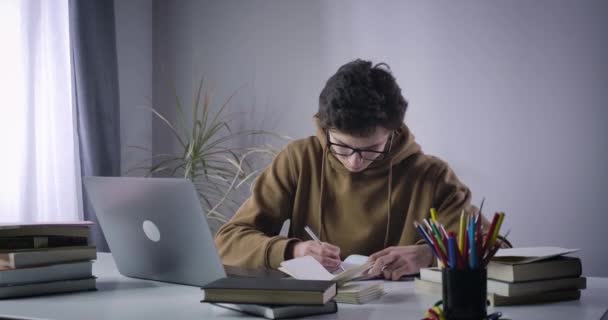 冷静点，白人男孩在笔记中犯了错误，然后把纸屑扔到相机上。大学生为大学做项目.教育过程，智力，生活方式。Cinema 4k ProRes HQ. — 图库视频影像