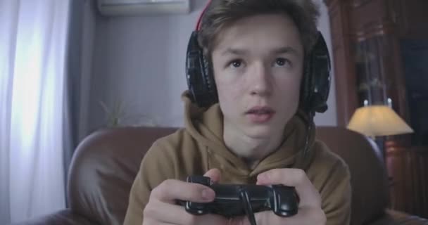 Gros plan portrait d'une adolescente brune aux yeux bruns dans un casque à l'aide d'une console de jeu. Garçon concentré jouant à un jeu vidéo à la maison. Mode de vie, jeu, dépendance. Siège social Cinema 4k ProRes . — Video