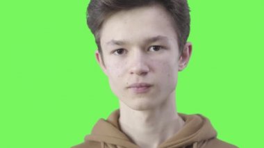 Esmer, beyaz bir çocuğun şakakta parmak bükmesi. Ciddi bir gencin çılgın davranışlar sergileyen portresi. Yanlış anlama, şaşkınlık, yanlış yorumlama. Kromakey, yeşil ekran.