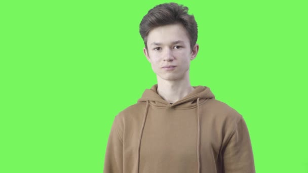 Portrait d'un adolescent caucasien souriant montrant la forme du cœur avec les mains. Aimant jeune garçon brune posant sur fond vert. Sentiments, amour, romance, mode de vie. Chromakey . — Video