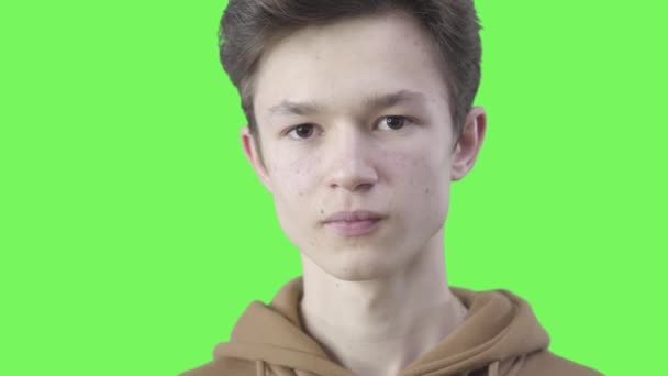 Gros plan de la brune garçon caucasien tordant doigt au temple. Portrait d'un adolescent sérieux montrant un geste fou de noix. Incompréhension, étonnement, mauvaise interprétation. Chromakey, écran vert . — Video