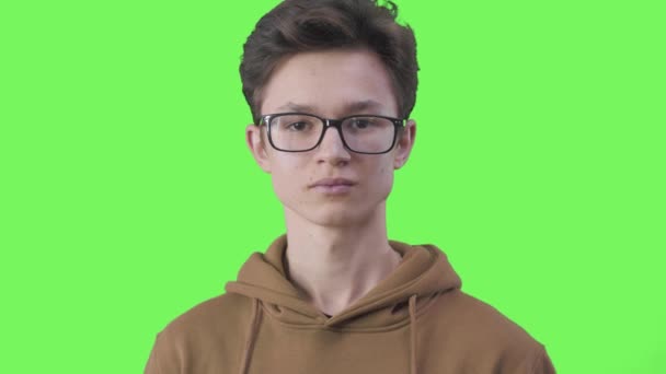 Intelligent male teenager putting eyeglasses down and looking at camera, close-up. Portrait of nerd Caucasian boy posing at green screen chromakey background. Intelligence, lifestyle. — Stock Video