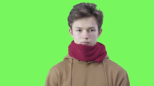 Porträt eines kranken Jungen, der vor grünem Hintergrund niest. Nahaufnahme eines tausendjährigen kaukasischen Teenagers in rotem Schal mit Erkältung und Grippe. Gesundheitskonzept, Covid-19-Pandemie. Chromakey. — Stockvideo