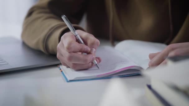 Ezeréves kaukázusi fiú kezei írnak a munkafüzetbe. Közelkép a férfi tenyérről tollal. Szorgalmas főiskolai hallgató, aki házi feladatot csinál. Oktatás, tanulás, tanulás, életmód. — Stock videók
